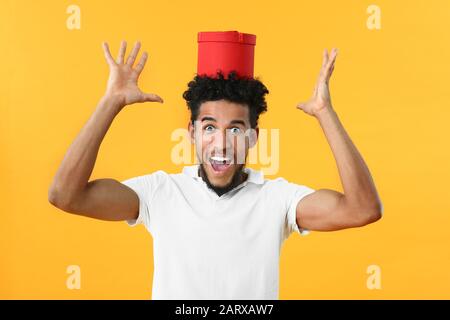 Porträt eines begeisterten afroamerikanischen Mannes mit Geschenk auf Farbhintergrund Stockfoto