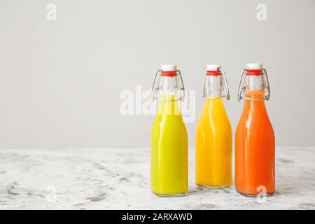 Flaschen mit frischen Säften auf grauem Hintergrund Stockfoto
