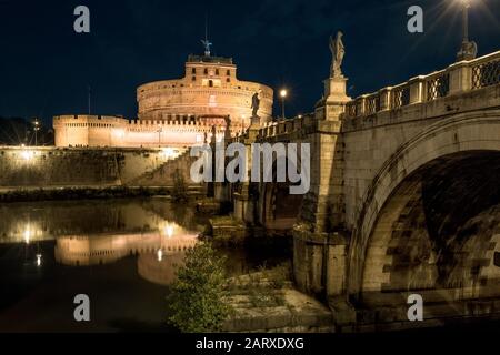 Castel und Ponte Sant'Angelo in der Nacht, Rom, Italien. Dieser Ort ist ein berühmtes altes Wahrzeichen Roms. Panorama der mittelalterlichen Burg und Brücke in Rom ci Stockfoto