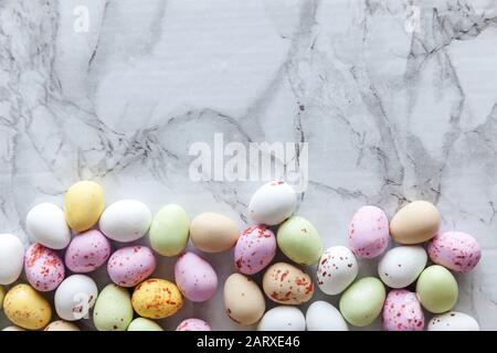 Frohe Ostern Konzept. Vorbereitung für den Urlaub. Ostern Eier in Pastellfarben Süßigkeiten Schokolade Bonbons auf trendige grauem Marmor Hintergrund. Einfache Minimalismus flach Ansicht von oben kopieren Raum Stockfoto