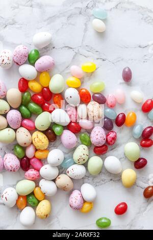 Frohe Ostern Konzept. Vorbereitung für den Urlaub. Ostern Süßigkeiten Schokolade Eier und fruchtgummi Bonbons auf trendige grauem Marmor Hintergrund. Einfache Minimalismus flach Ansicht von oben kopieren Raum Stockfoto