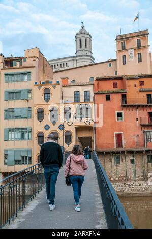 Menschen, die auf einer Brücke über den Fluss Onyar spazieren, Die Häuser am Fluss Onyar mit der Kathedrale im Hintergrund, Girona, Katalonien, Spanien Stockfoto