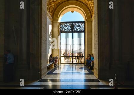 Das Sonnenlicht scheint auf Touristen, während sie vor den Toren des Petersdoms in der Vatikanstadt warten. Stockfoto