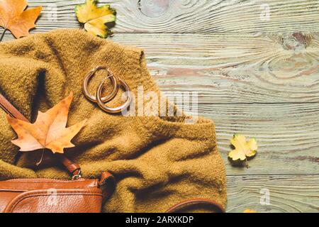 Schöne Herbstkomposition mit Kleidung und Blättern auf Holzhintergrund Stockfoto