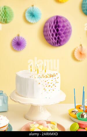 Leckere Süßwarenbar für Geburtstagsparty auf dem Tisch vor farbenem Hintergrund Stockfoto
