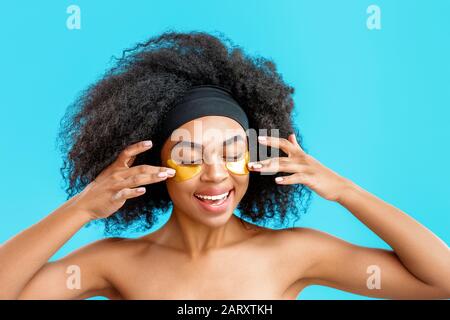 Porträt einer schönen afroamerikanischen Frau mit Unteraugenflecken auf Farbhintergrund Stockfoto