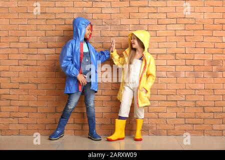 Modische kleine Kinder in Herbstkleidung in der Nähe der Ziegelwand Stockfoto