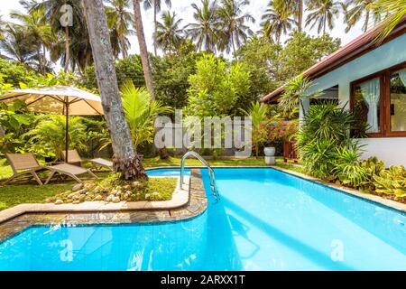 Sri Lanka - 4. November 2017: Pool mit Sonnenschirm und Strandbetten im Hinterhof eines tropischen Luxushotels. Schöner Swimmingpool mit blauem, sauberem Wasser Stockfoto