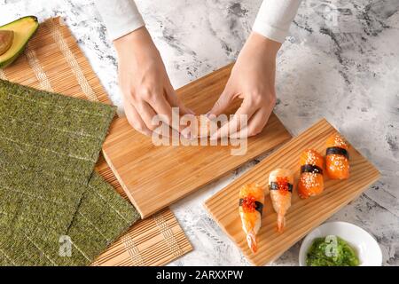 Frau, die zu Hause leckeres Sushi zubereitet Stockfoto