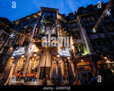 Strasbourg, Frankreich - 24. Dezember 2018: Niedriger weiter Blick auf das Restaurant Le Gruber auf der berühmten Fußgängerzone mit Touristen, die die jährlichen Dekorationen des Weihnachtsmarktes entdecken Stockfoto