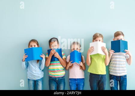 Überraschte kleine Kinder mit Büchern auf Farbhintergrund Stockfoto