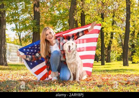 Fröhliche Frau und Hund mit Nationalflaggen der USA im Park. Gedenkfeier Stockfoto