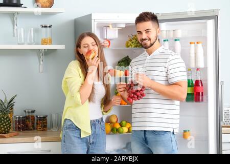 Junges Paar, das Essen aus dem Kühlschrank in der Küche nimmt Stockfoto