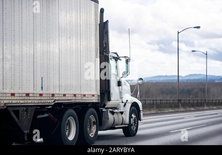 Big Rig White Day CAB Diesel Semi-Truck mit Dachspoiler für lokale Lieferungen Transport von kommerzieller Ladung im trockenen Transporter Sattelanhänger Fahren auf dem Wi Stockfoto