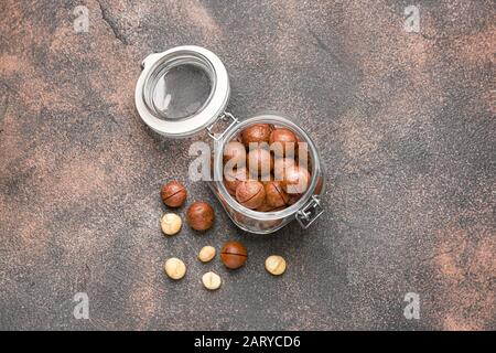 Glas mit Macadamia-Nüssen auf grauem Hintergrund Stockfoto