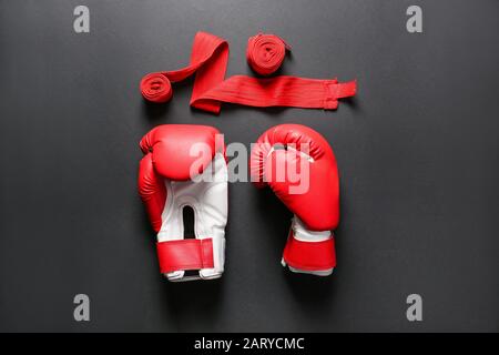 Boxhandschuhe und Handgelenkbänder auf dunklem Hintergrund Stockfoto