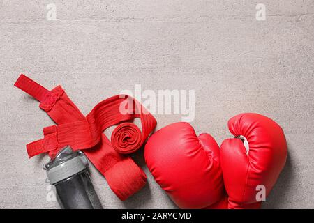 Boxhandschuhe, Handgelenkbänder und eine Flasche Wasser auf hellem Hintergrund Stockfoto