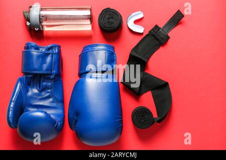 Boxhandschuhe, Handgelenkbänder, Flasche Wasser und Mundstück auf Farbhintergrund Stockfoto