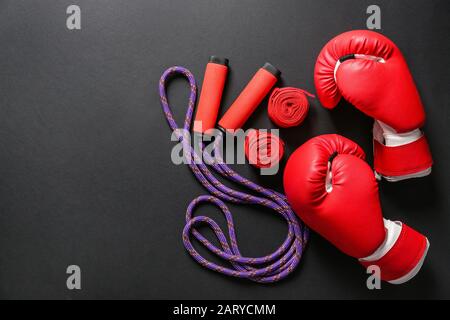 Boxhandschuhe, Handgelenkbänder und Springseil auf dunklem Hintergrund Stockfoto