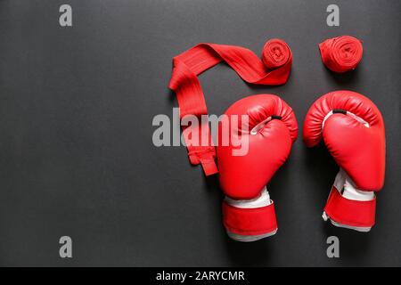 Boxhandschuhe und Handgelenkbänder auf dunklem Hintergrund Stockfoto