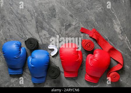 Boxhandschuhe, Handgelenkbänder und Mundstück auf grauem Hintergrund Stockfoto