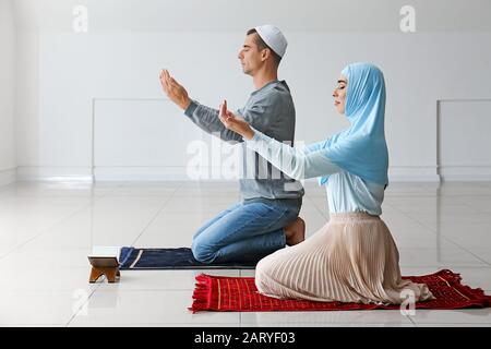 Muslimisches Paar betet im Zimmer Stockfoto