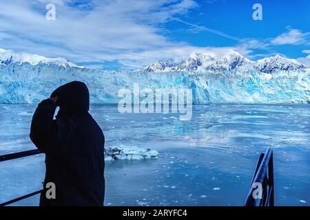 Der schwarze Mann blickt auf den Hubbard-Gletscher. Dies ist eine Bootstour in Alaska auf einem Kreuzfahrtschiff von Juneau. Gangway ist für ein kleines Ausflugsboot eingerichtet. Stockfoto