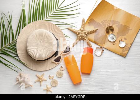 Set mit Strandzubehör mit Karte und Kompass auf weißem Holzhintergrund Stockfoto