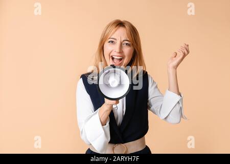Reife Frau mit Megafon auf farbigen Hintergrund Stockfoto