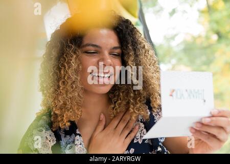 Lächelnde Frau liest Dankeskarte Stockfoto