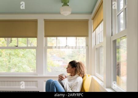 Frau hält Tasse auf dem Stuhl Stockfoto