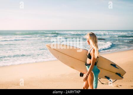 Frau in Neoprenanzug mit Surfbrett am Strand Stockfoto