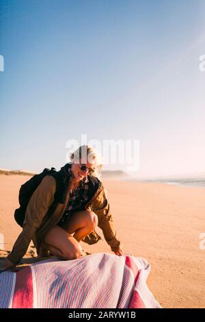 Lächelnde Frau, die Handtuch am Strand legt Stockfoto