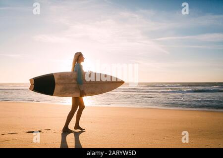 Frau in Neoprenanzug mit Surfbrett am Strand Stockfoto