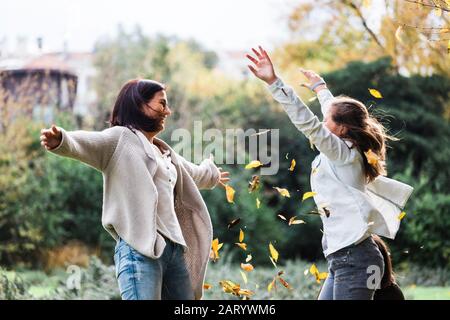 Mutter und Tochter spielen im Herbstlaub Stockfoto