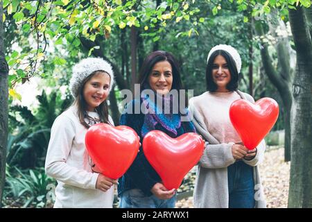 Mutter und Töchter halten Herzballons von Bäumen Stockfoto