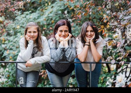 Mutter und Töchter lächeln und lehnen sich an Geländer Stockfoto