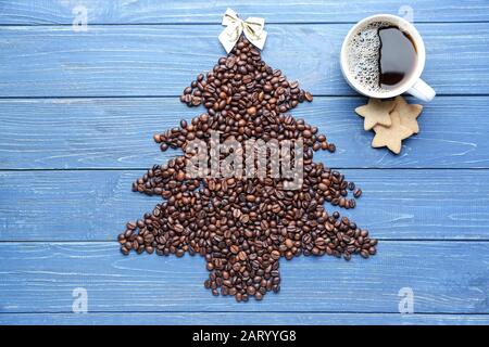 Weihnachtsbaumform aus Kaffeebohnen auf Farbhintergrund Stockfoto