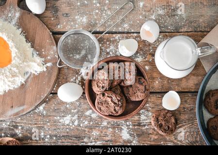 Schmackhafte Schokoladenspanplätzchen mit Milch, Mehl und Eiern auf Holztisch Stockfoto