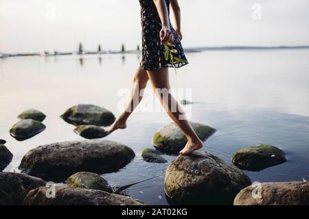 Barfuß Frau tritt auf Felsen im Meer Stockfoto