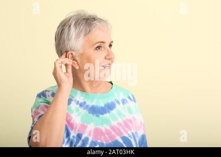 Seniorin mit Hörgerät auf Farbhintergrund Stockfoto