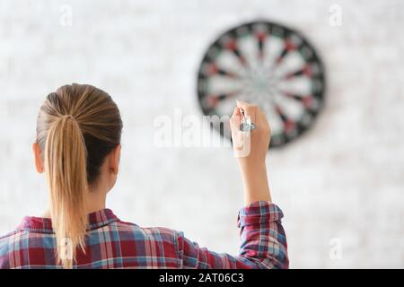 Junge Frau, die Darts in Innenräumen spielt Stockfoto