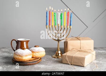 Menorah, Donuts und Geschenke für Hanukkah auf dem Tisch Stockfoto