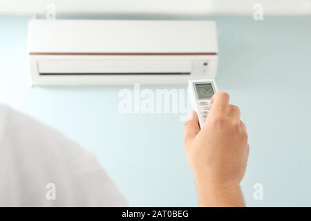 Junger Mann Einschalten der Klimaanlage zu Hause Stockfoto