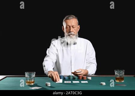 Reifer männlicher Banker am Tisch im Casino Stockfoto