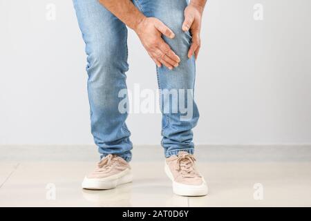 Reifer Mann, der an Schmerzen im Knie in der Nähe der Wand leidet Stockfoto