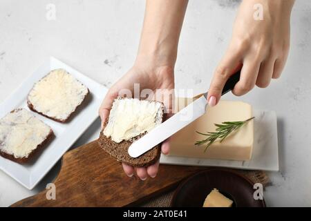 Frau, die frische Butter auf eine Scheibe Brot streut Stockfoto