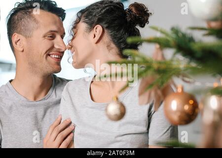 Fröhliches junges Paar in der Nähe des Weihnachtsbaums zu Hause Stockfoto