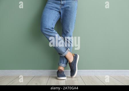 Junger Mann in stylischen Schuhen in der Nähe der Farbwand Stockfoto
