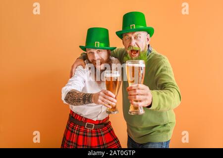 Bärtige Männer mit Biergläsern auf Farbhintergrund. St. Patrick's Day Celebration Stockfoto